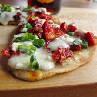 Piece of skillet pizza with dried tomatoes and a beer crust