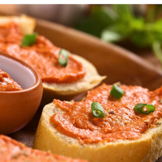 Tomato butter on rustic thick bread with scallions as garnish on top.