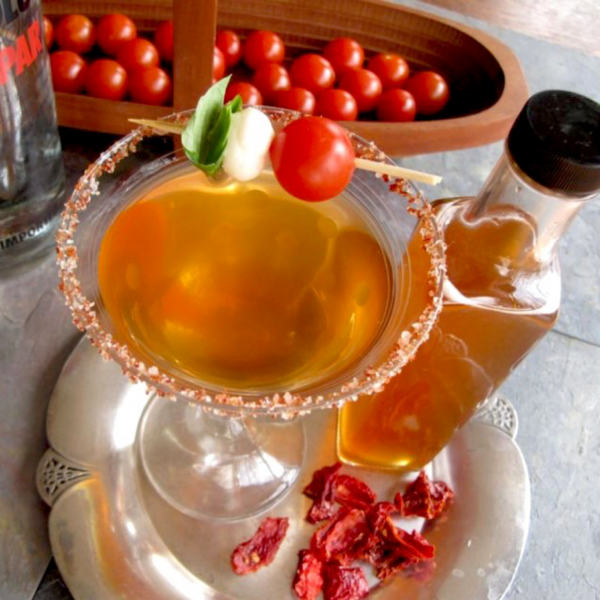 Martini made with tomato water shrub syrup with cherry tomatoes in background