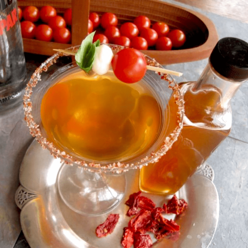 Martini made with tomato water shrub syrup with cherry tomatoes in background