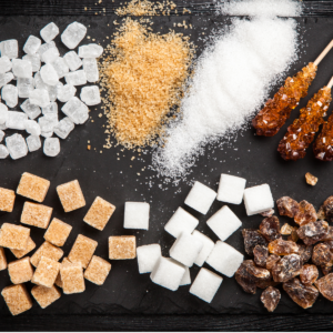 A range of different types of sugar laid out on a black surface.
