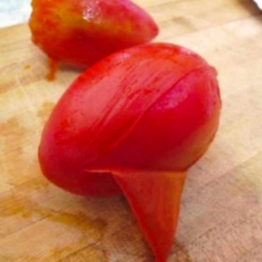 Peeling the skin off of blanced Roma tomatoes