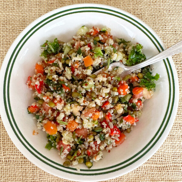Quinoa salad with cherry tomatoes in a white bowl.