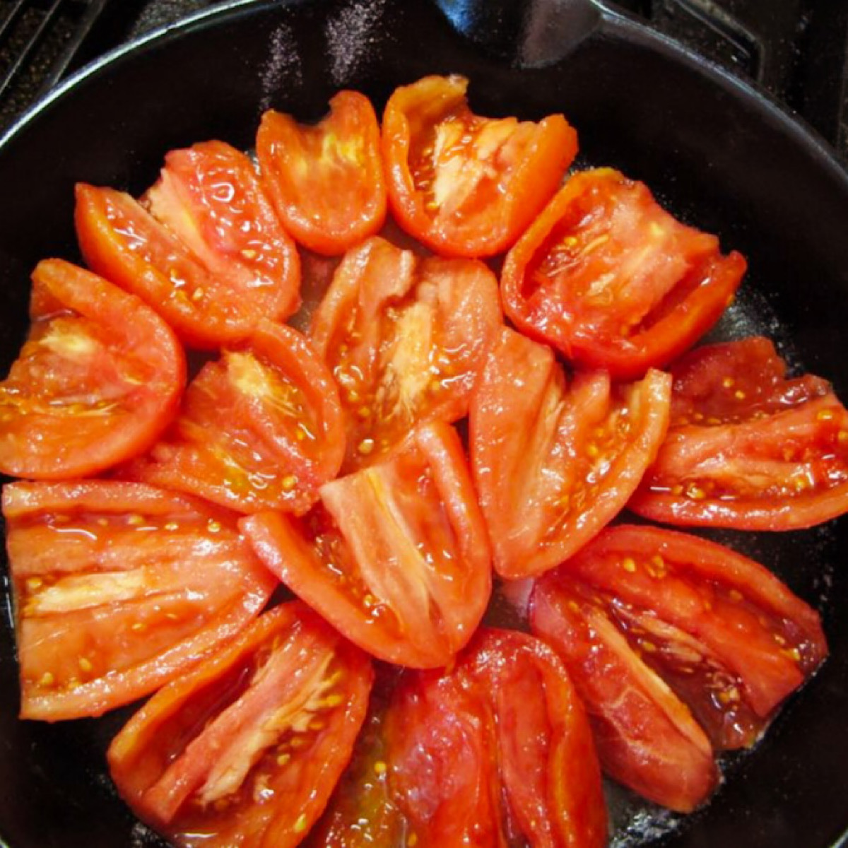 Roma tomatoes arranged in a circle pattern in a skillet.
