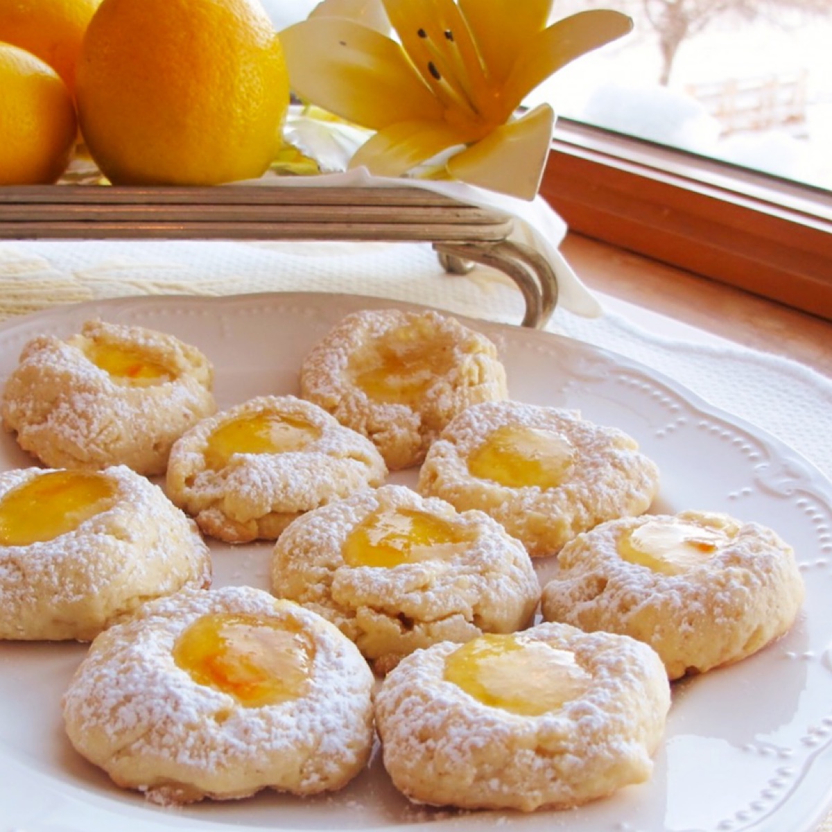 Thumbprint cookies with lemon marmalade filling on a white plate.