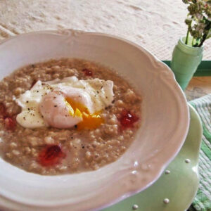 Bowl of oatmeal with poached egg and raspberry hot pepper jelly