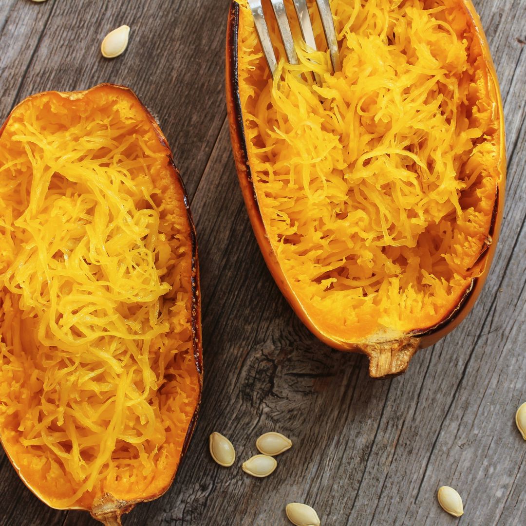 Cooked spaghetti squash with fork pulling out the strands.
