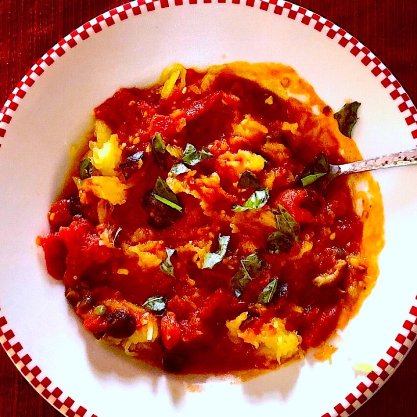 Bowl of Italian puttanesca sauce on a bed of spaghetti squash.