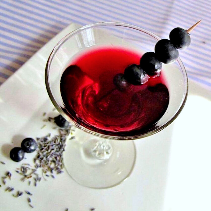 Top down view of blueberry martini with lavender flowers and blueberries on the plate..