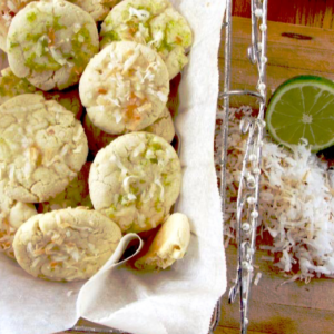 Coconut lime cookies in a basket with white parchment paper and a lime and coconut on the side.