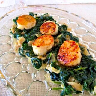 Seared scallops on a bed of creamed spinach with onions.