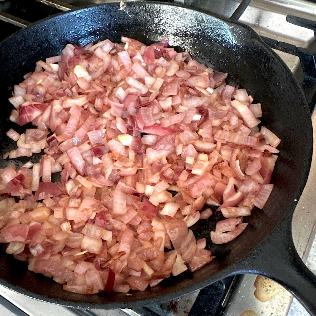 Onions cooking in a black cast iron skillet.