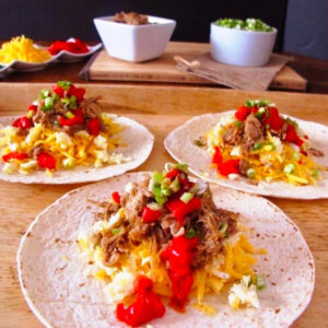 3 taco fillings on soft shell flour tortillas laid out on a cutting board.