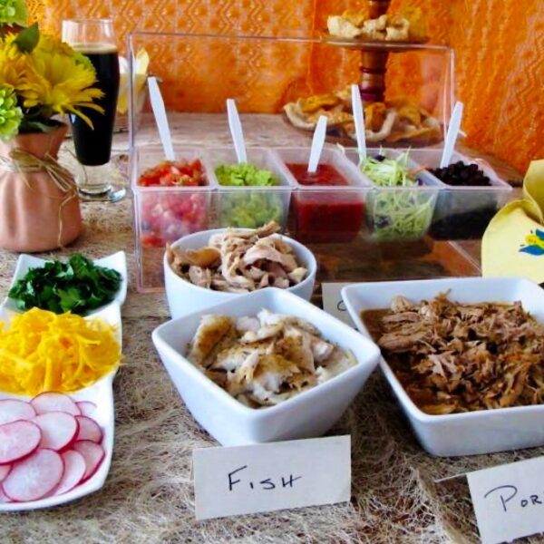 A table of various taco fixings for a taco bar