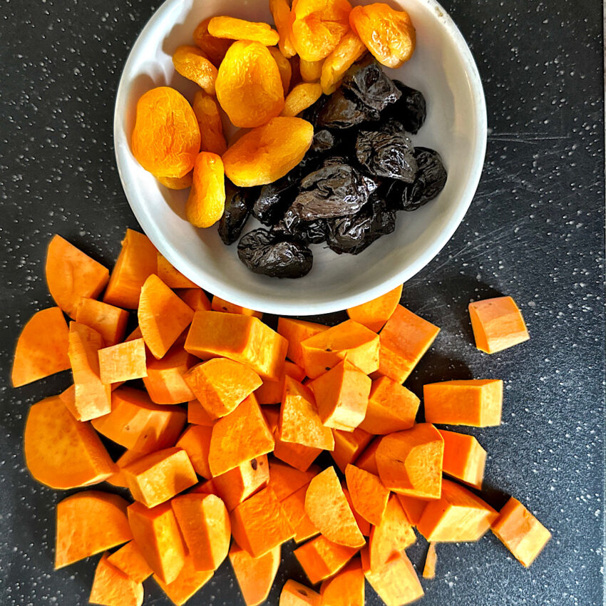Sweet potatoes cut into bite-size pieces and a small bowl of dried apricots and dried plums.