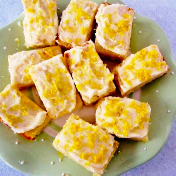 Squares of Limoncello Blondie bars on a light green plate.