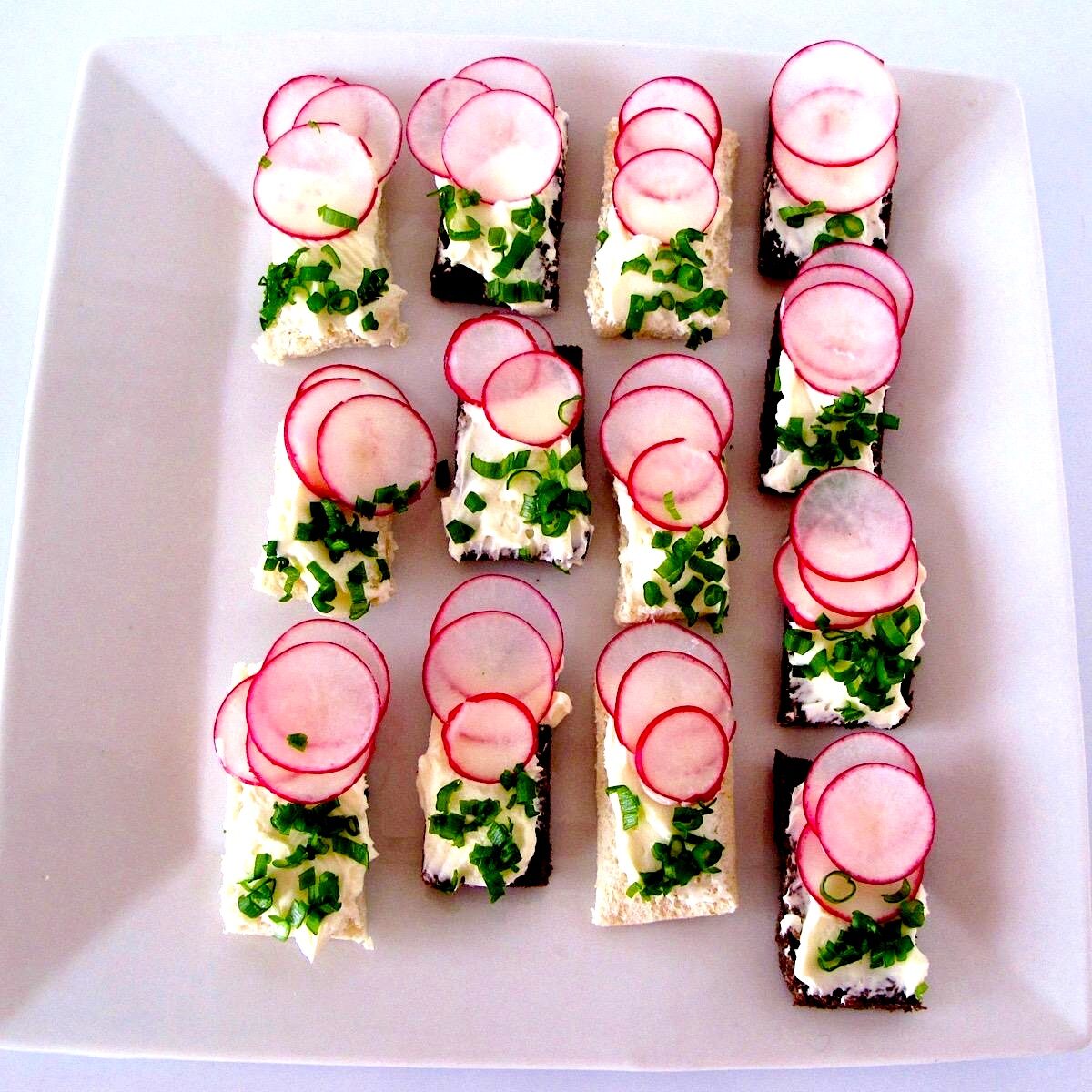 Radish and cream cheese appetizers with herbs on a white plate for spring afternoon tea.