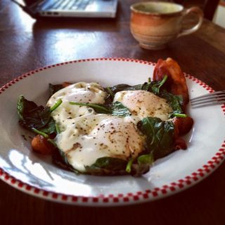 Slow carb breakfast of bacon and eggs baked on top of a bed of spinach