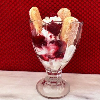 Raspberry trifle in a parfait glass with 3 ladyfingers.