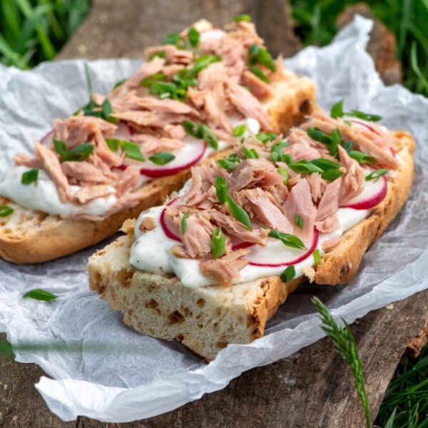 Tuna nicoise sandwich on a baguette cut in half and laid out on parchment paper.