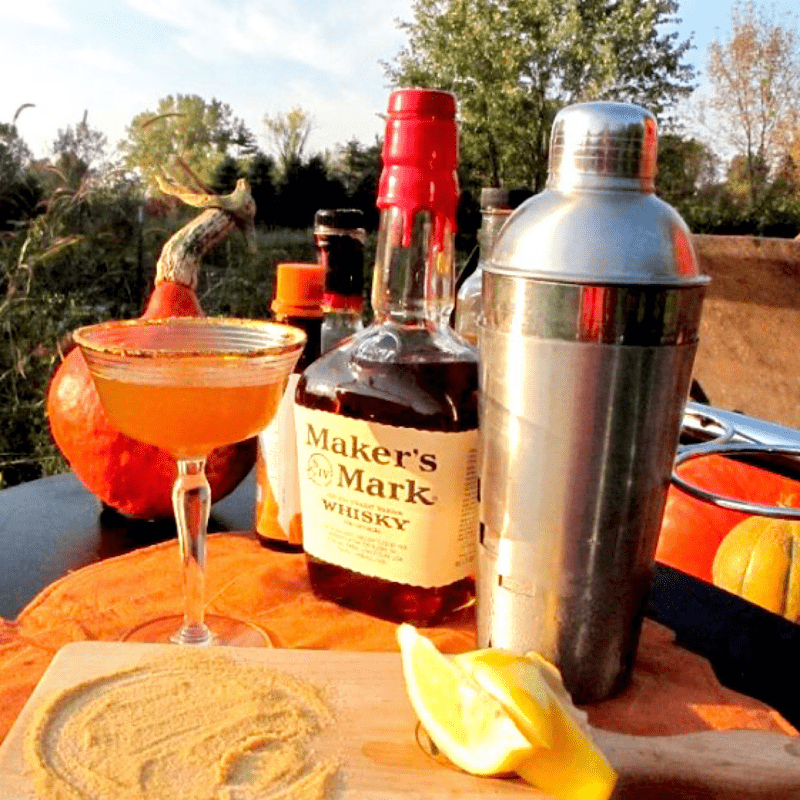 Pumpkin martini surrounded by ingredients and cocktail tools.