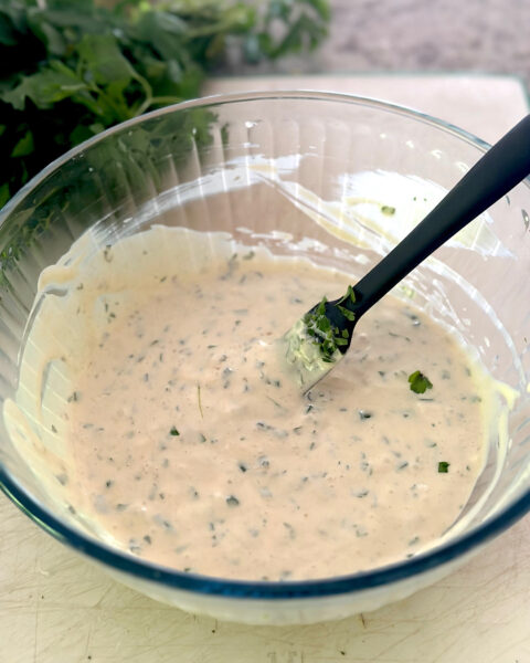 A bowl full of the binding ingredients for fish cakes including mayonnaise, mustard, sour cream and spices. 