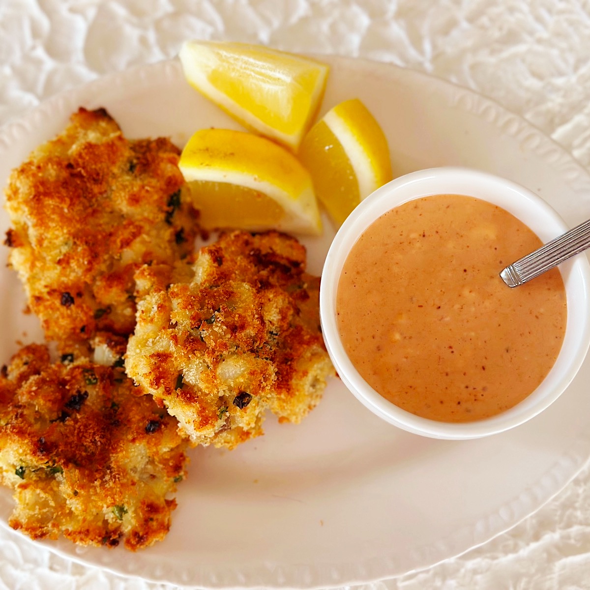 3 fish cakes with lemon garnish and a Southern comeback dipping sauce.