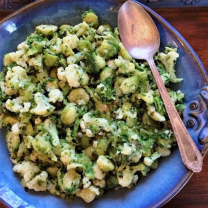 Broccoli cauliflower and brussels medley of vegetables in blue bowl.