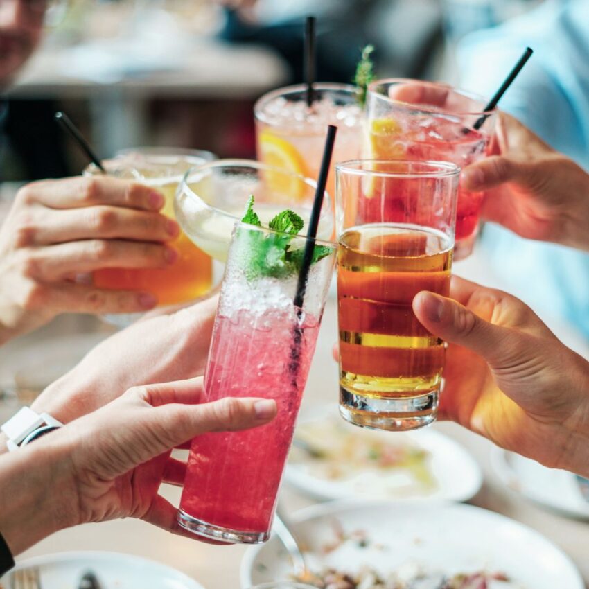 People’s hands toasting with drinks, alcoholic and non-alcoholic.