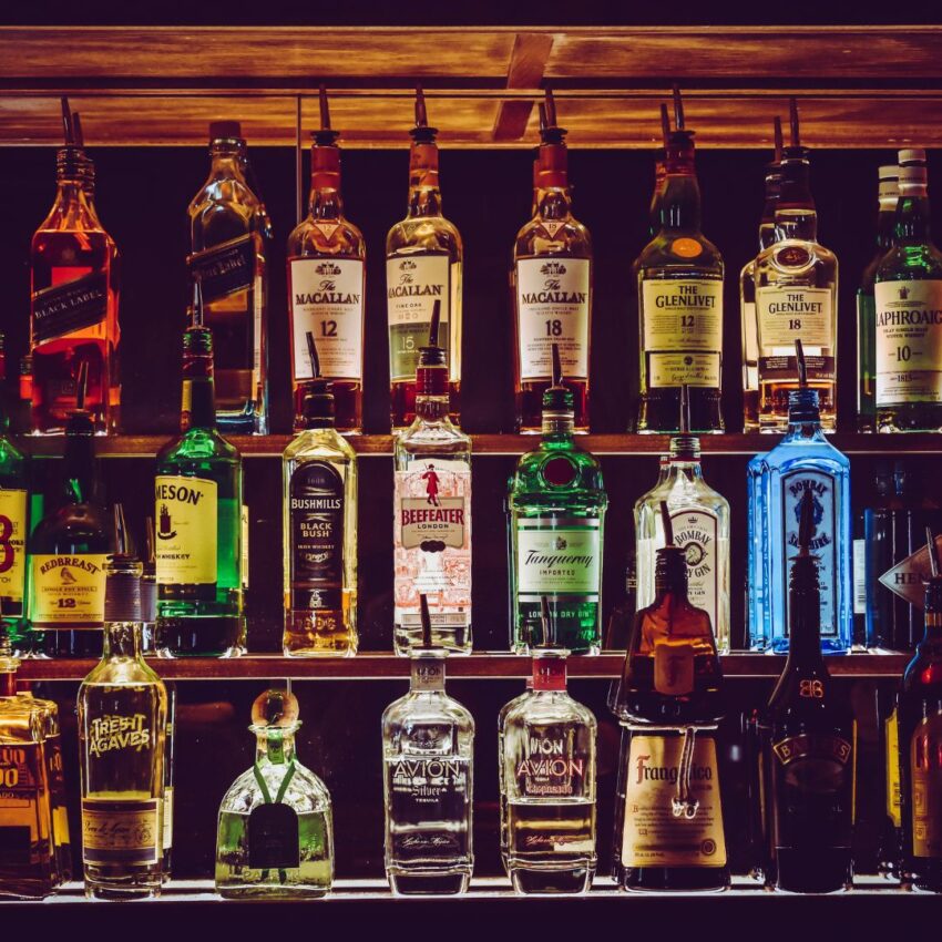 An arrangement of various alcohol bottles on a bartender’s shelf.