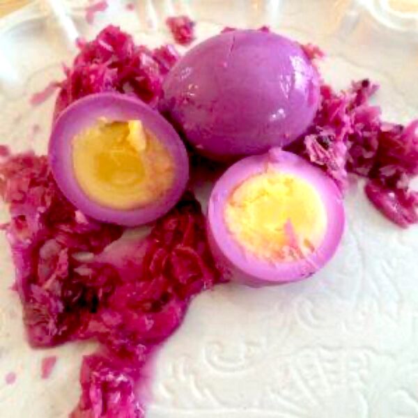 Example of pickled red cabbage eggs cut in half, with shredded red cabbage surrounding them.