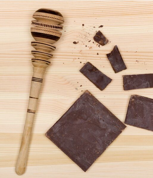 A Mexican molinillo used for whipping chocolate and several squares of Mexican chocolate.