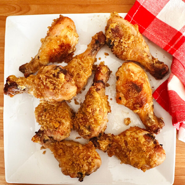 chicken legs with low carb breading mixture and Dijon mustard on a white plate.