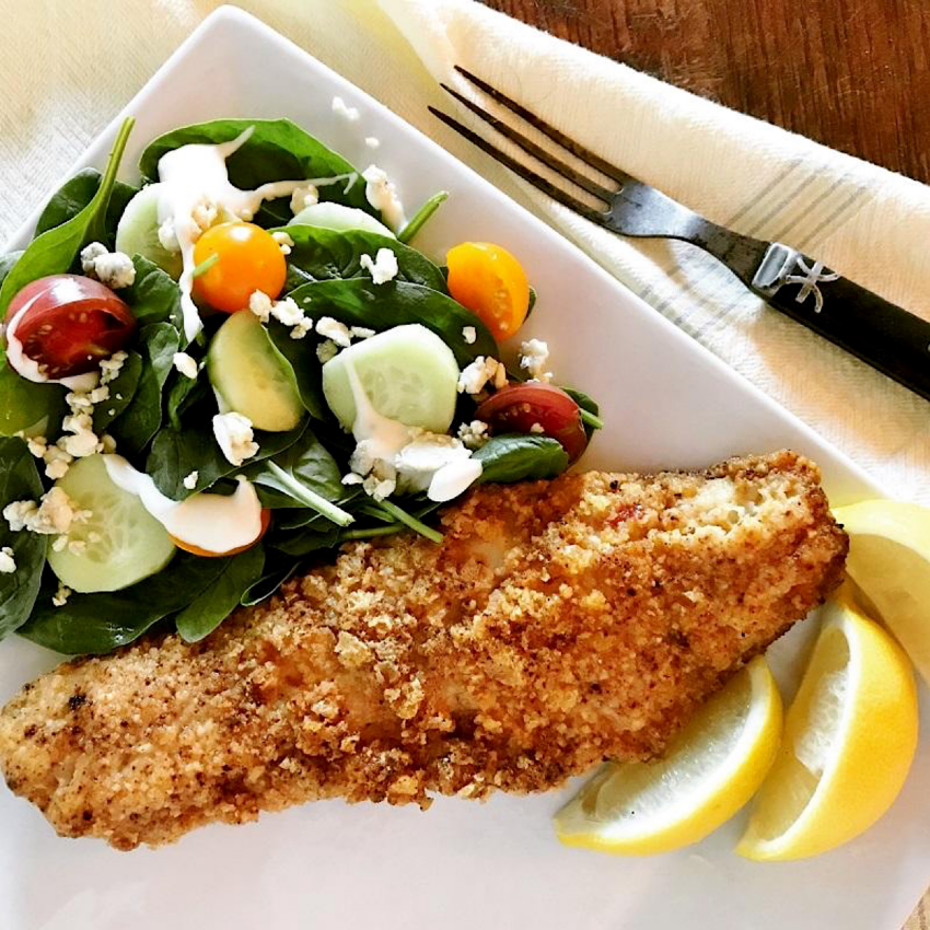 Fish filet fried in a low carb breading, with a side of green tossed salad and two lemon wedges.