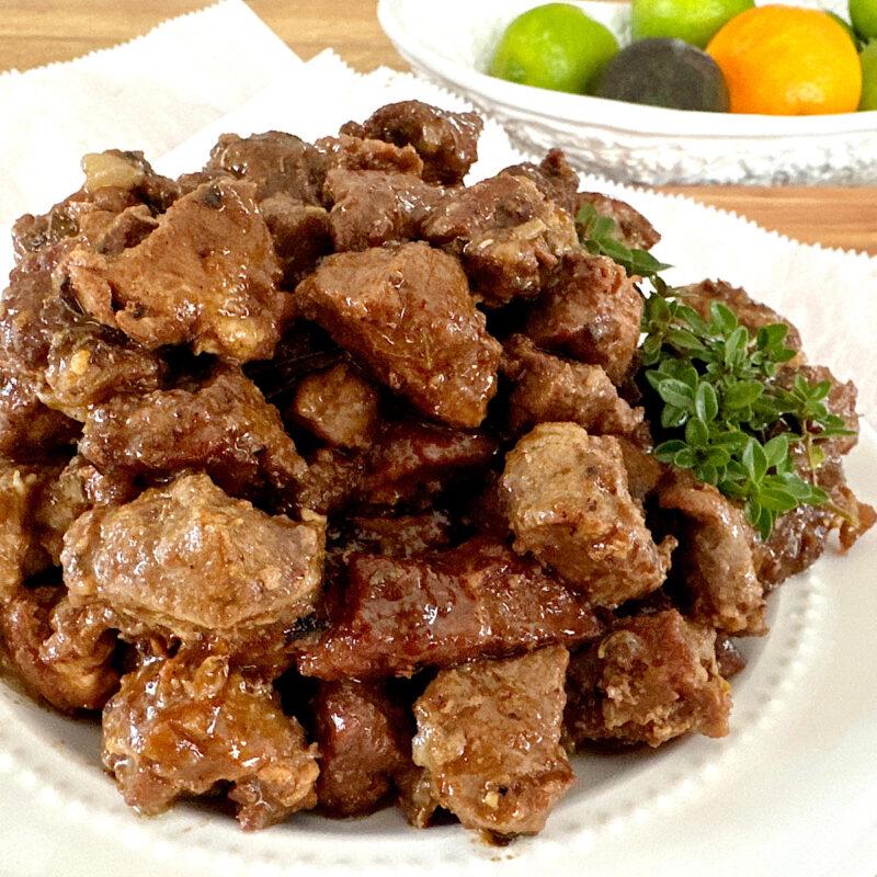 Plate of finished carnitas with a sprig of thyme as a garnish.
