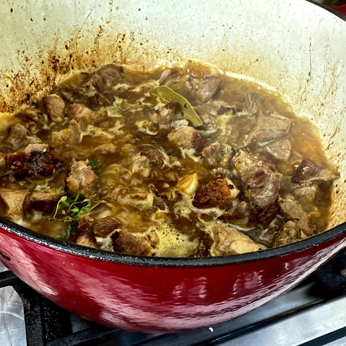 Dutch oven with all of carnitas ingredients simmering for 2 hours.