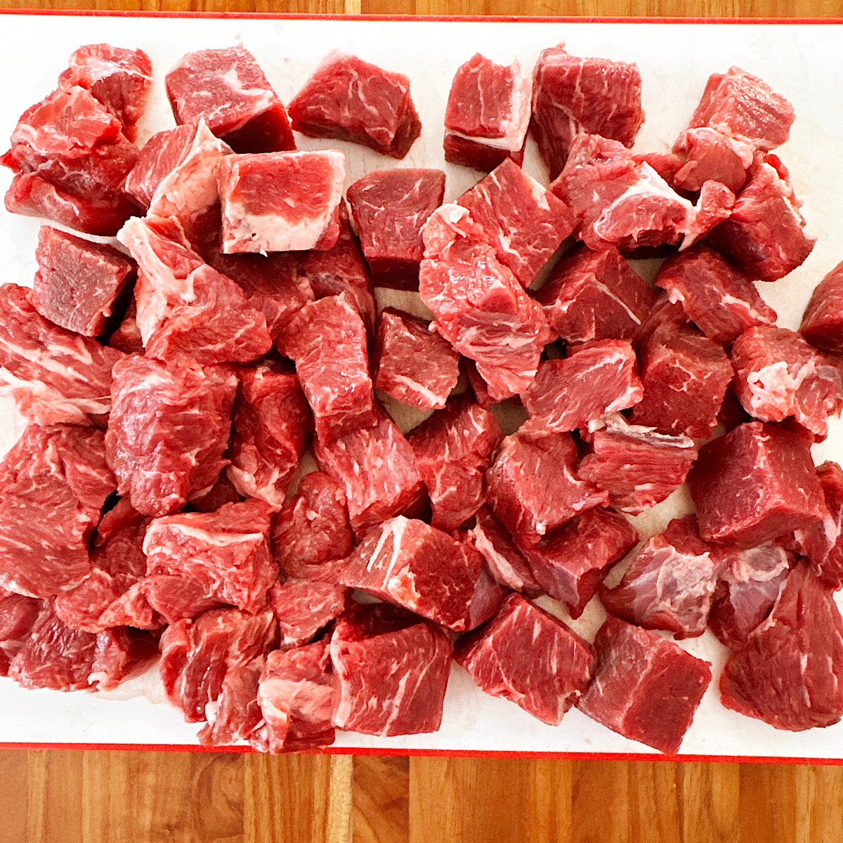 Chuck roast cut into 1-inch pieces on white cutting board.