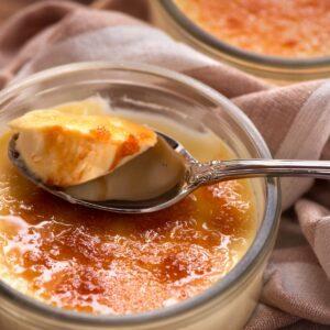 Creme brûlée with a bite on a spoon showing the creamy texture