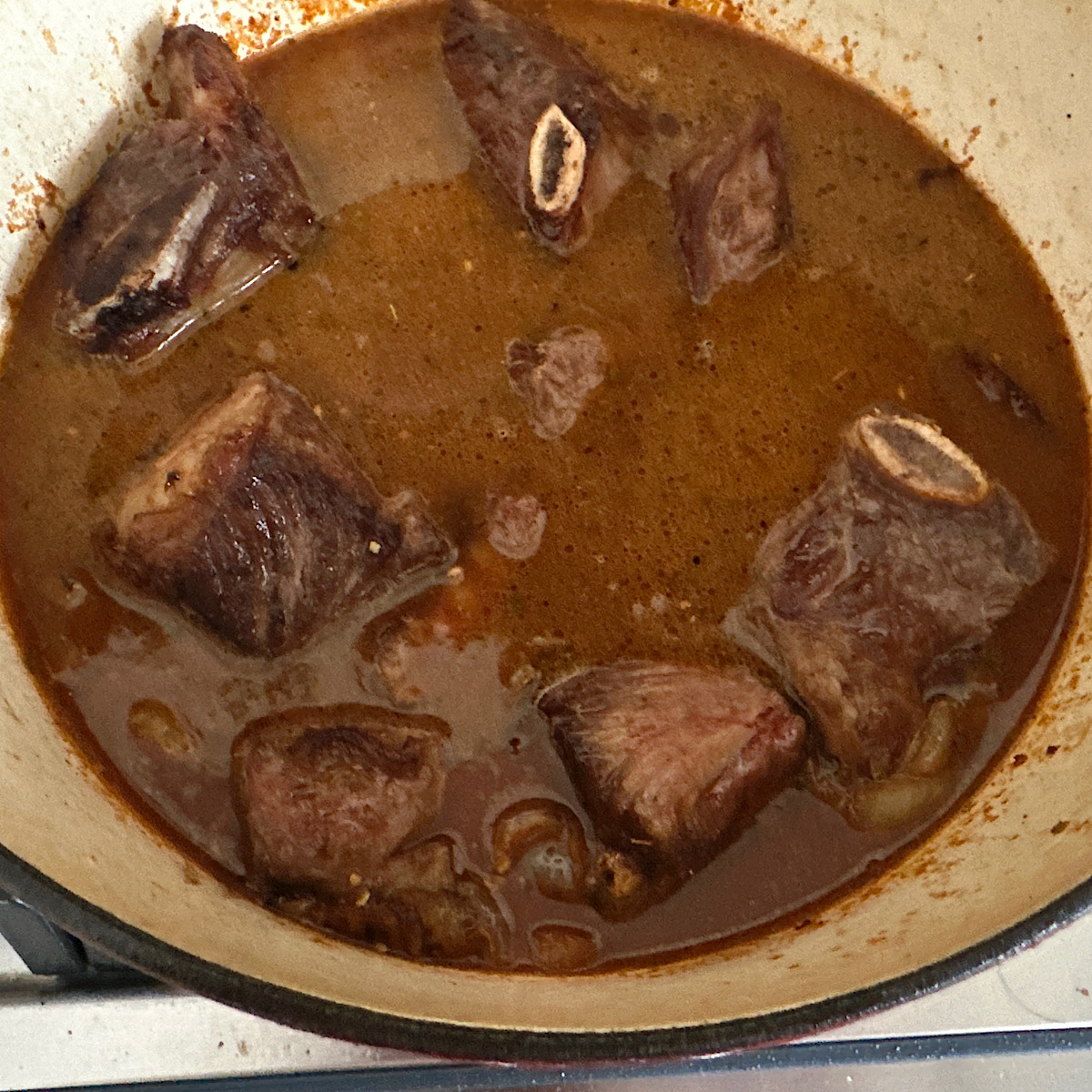 Beef short ribs in dutch oven with enchilada sauce.