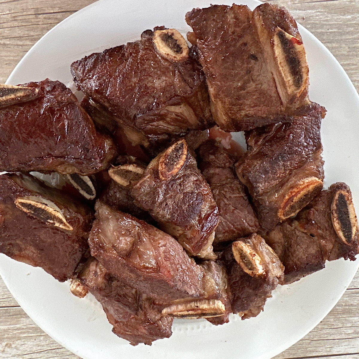 Beef short ribs sliced to 3” pieces on a white plate.