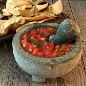 Fresh tomato salsa in a mortar and pestle with a side of chips.