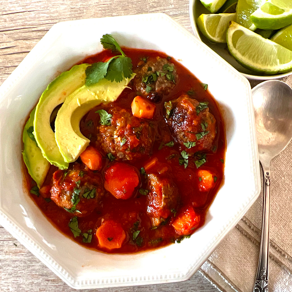 Bowl of Mexican meatball souop (Albondigas) with avocado garnish.