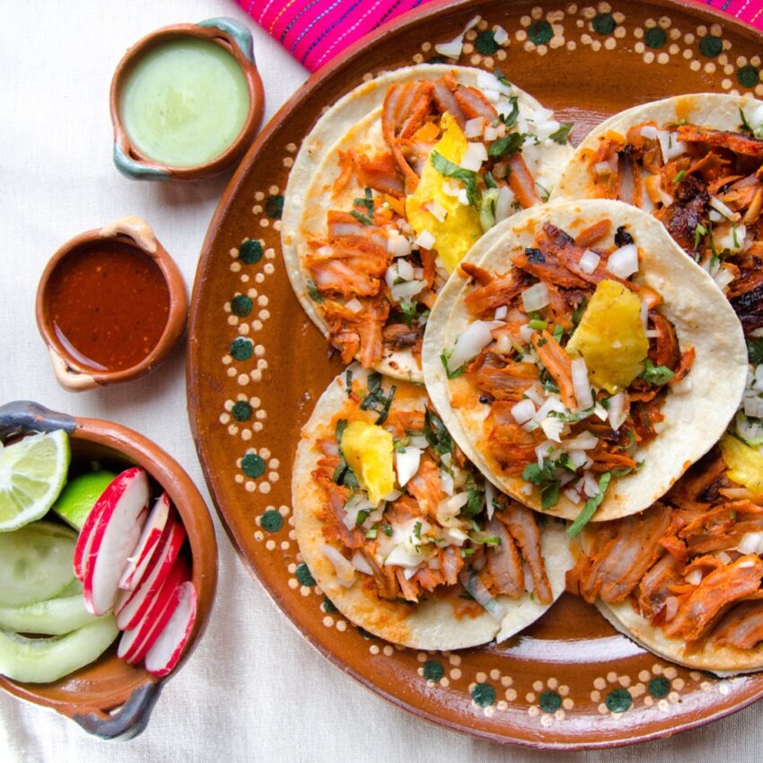 Plate of tacos al pastor with 3 condiments on the side.