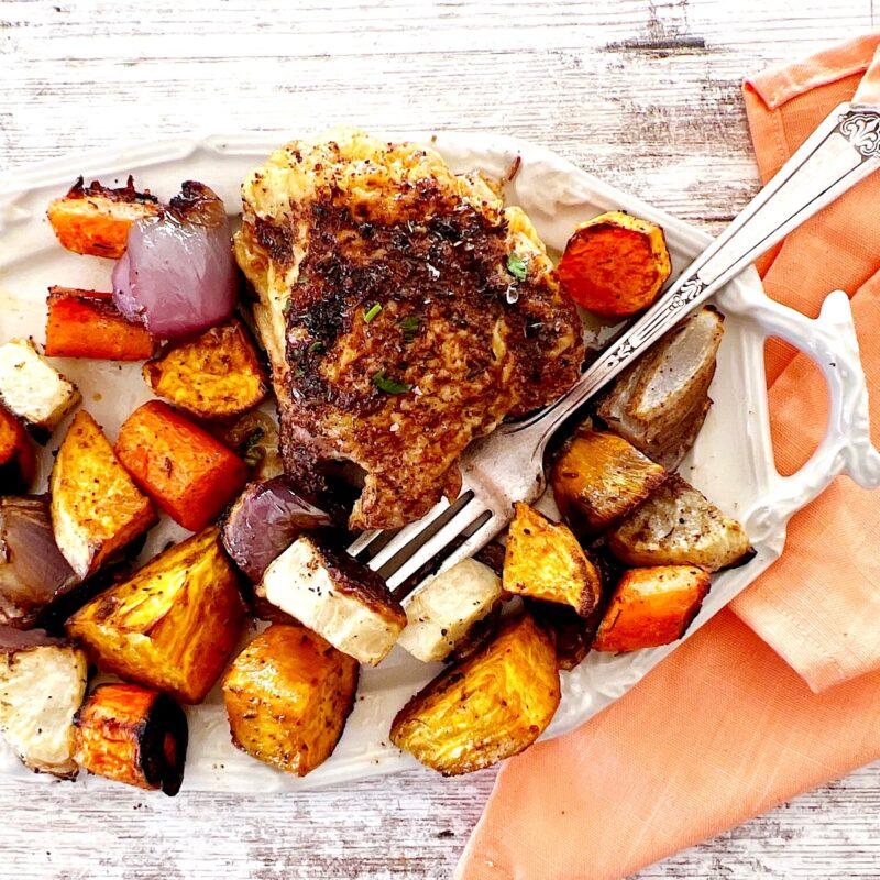 White tray of chicken and root vegetables made as a sheet pan dinner.