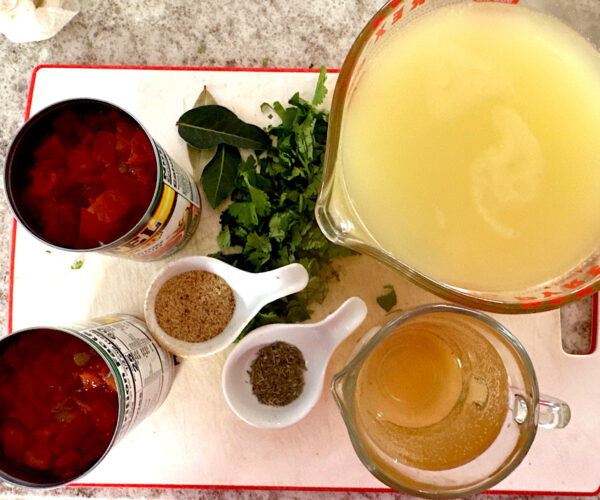 Tomatoes, cilantro, chicken broth, wine, and spices ready for adding to soup.