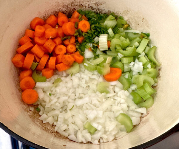 Veggies cooking in a dutch oven for the first step of the seafood stew.