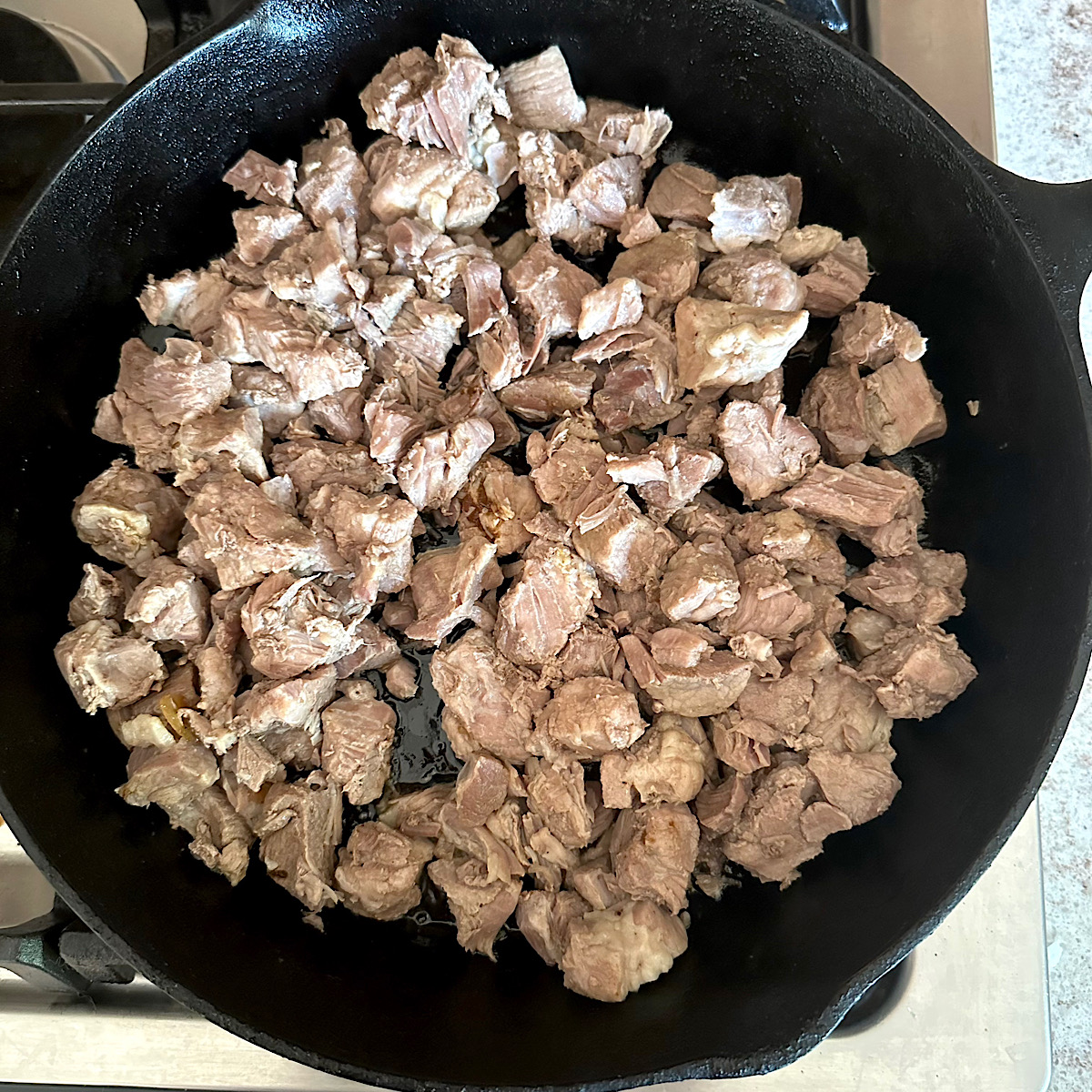 Pork cubes braising in skillet