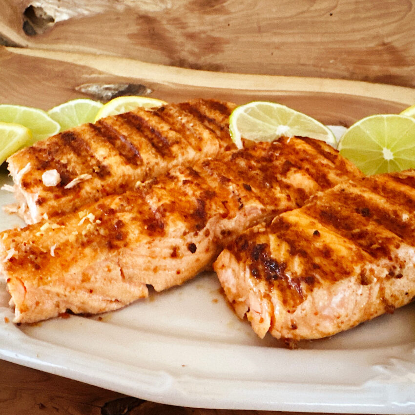 3 indoor-grilled salmon filets with lime slices on a white plate.
