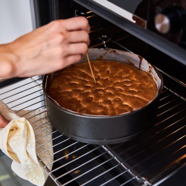 Testing cheesecake with a toothpick to make sure it is not overcooked.