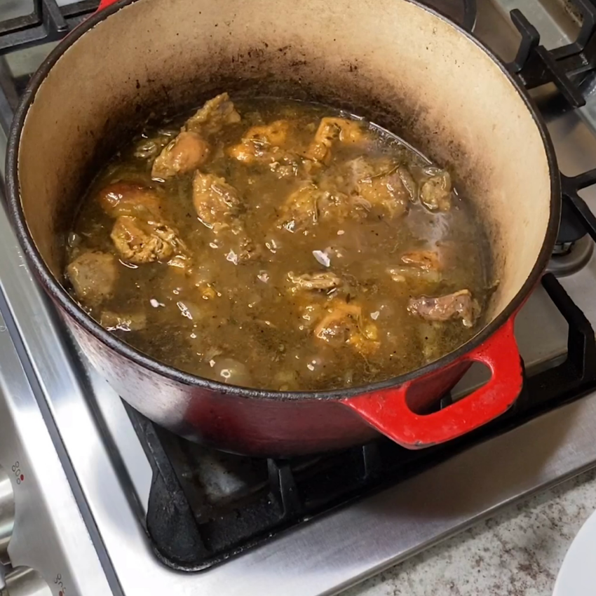 Large pot of pheasant cooking in a cider-onion mixture.